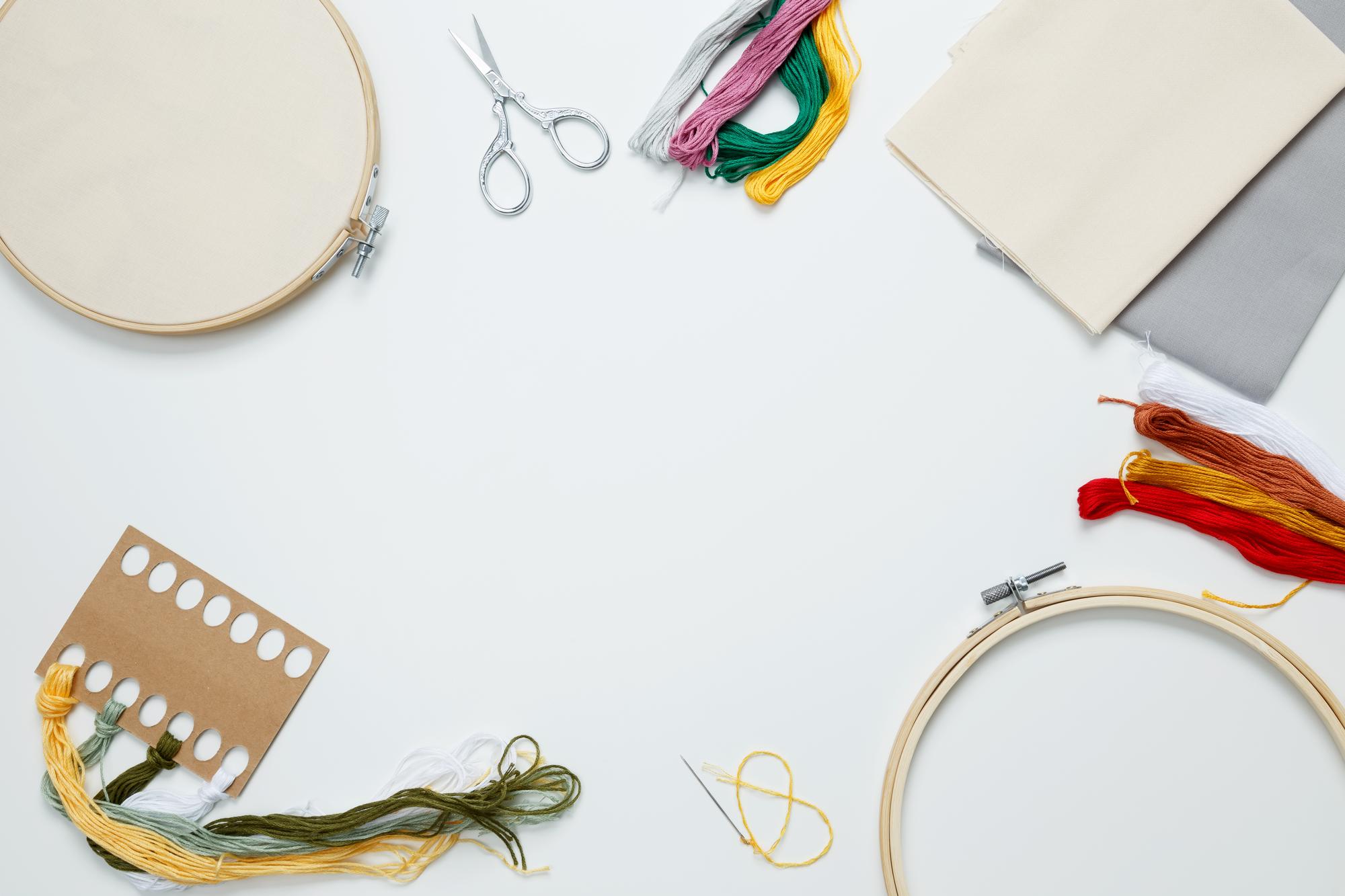 Workspace with embroidery hoops and threads on table